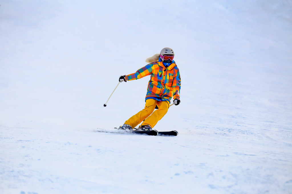 Skier in mask slides fast while skiing from slope